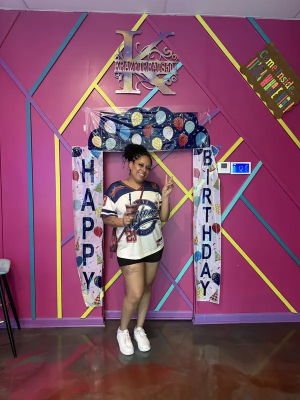 Birthday guest posing under the Happy Birthday arch with a daiquiri