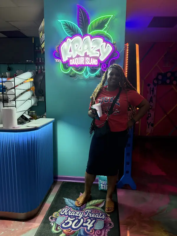 Guest posing with a daiquiri under the Krazy Daiquiri Island neon sign